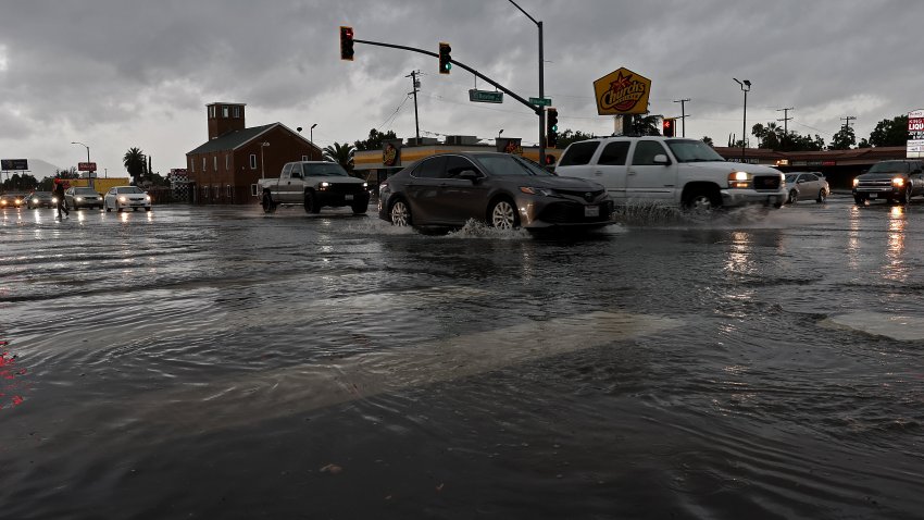 Autos circulan por una intersección inundada mientras la tormenta tropical Hilary atraviesa la zona el 20 de agosto de 2023 en San Bernardino, California.