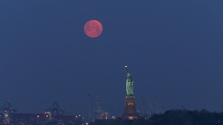 Moon rises behind statue of liberty