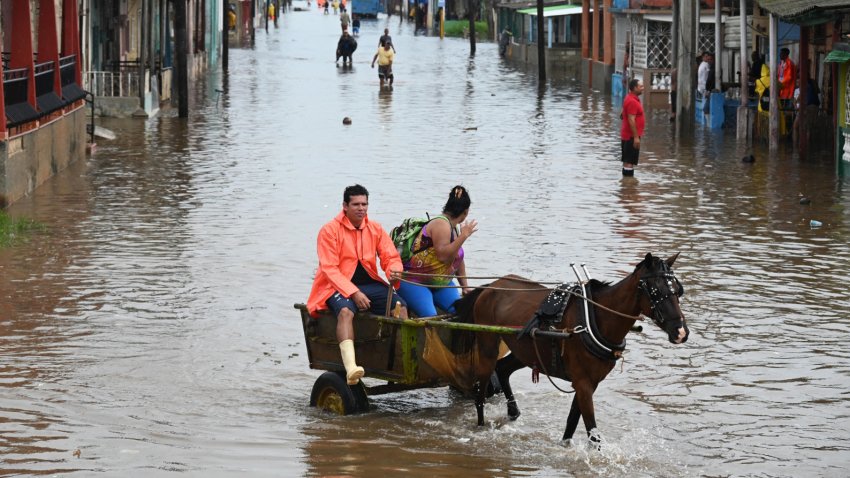 A couple ride a horse drawn carriage through a flooded street in Batabano, Mayabeque province, Cuba on August 29, 2023, during the passage of tropical storm Idalia. Tropical Storm Idalia strengthened into a hurricane this Tuesday and forecasters are forecasting it to become “extremely dangerous” before making landfall on Wednesday in Florida, US. (Photo by Yamil LAGE / AFP) (Photo by YAMIL LAGE/AFP via Getty Images)