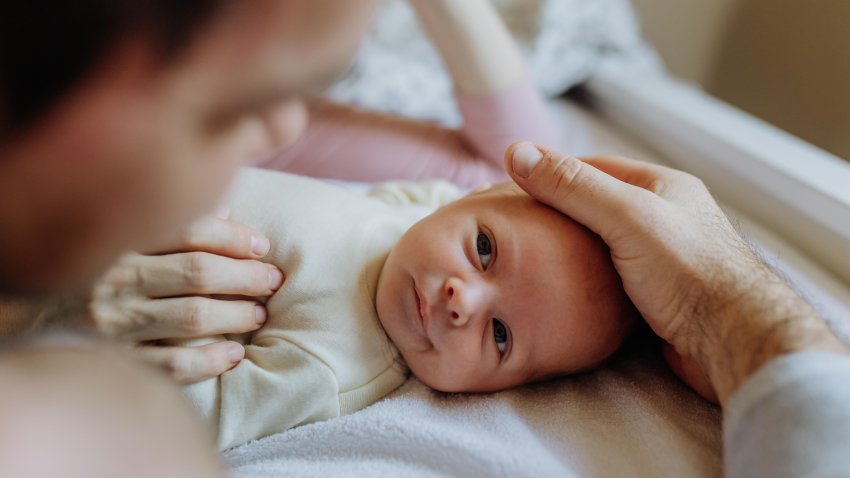 Close-up of parents cuddling their newborn baby.