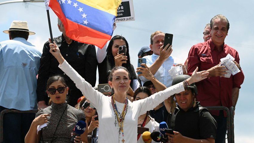 TOPSHOT – Venezuelan opposition leader Maria Corina Machado (C) holds a national flag atop a truck during a protest called by the opposition for election ‘victory’ to be recognised, in Caracas on August 17, 2024. Machado, who came out of hiding to attend the rally, vowed that anti-government protesters would remain out in force, as she addressed a protest in Caracas against Nicolas Maduro’s disputed reelection victory claim. (Photo by Federico PARRA / AFP) (Photo by FEDERICO PARRA/AFP via Getty Images)